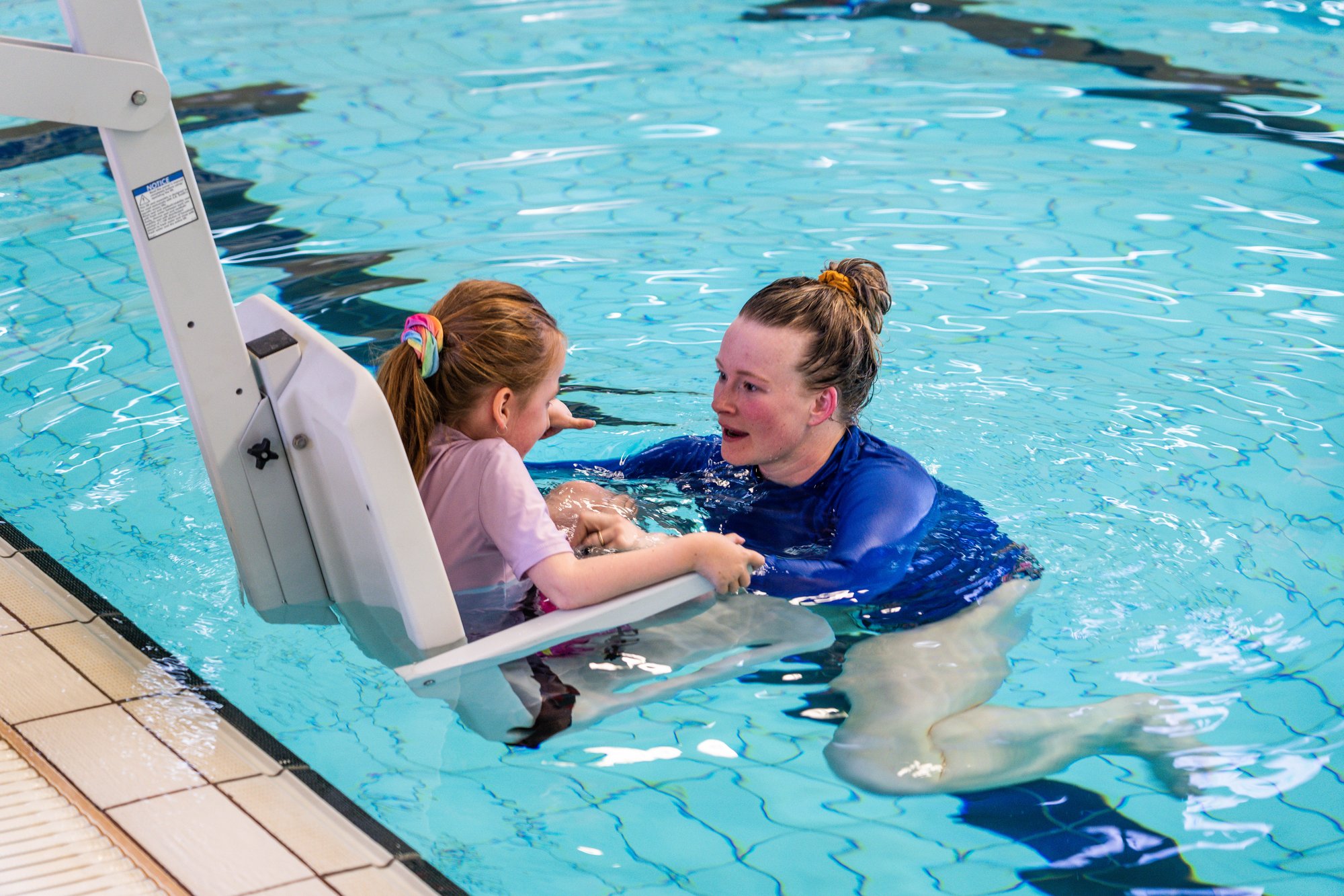 Swim teacher supporting a young child during practical training in an AUSTSWIM extension course.