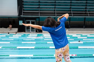 Swim teacher shadowing a swim stroke at a swimming pool.