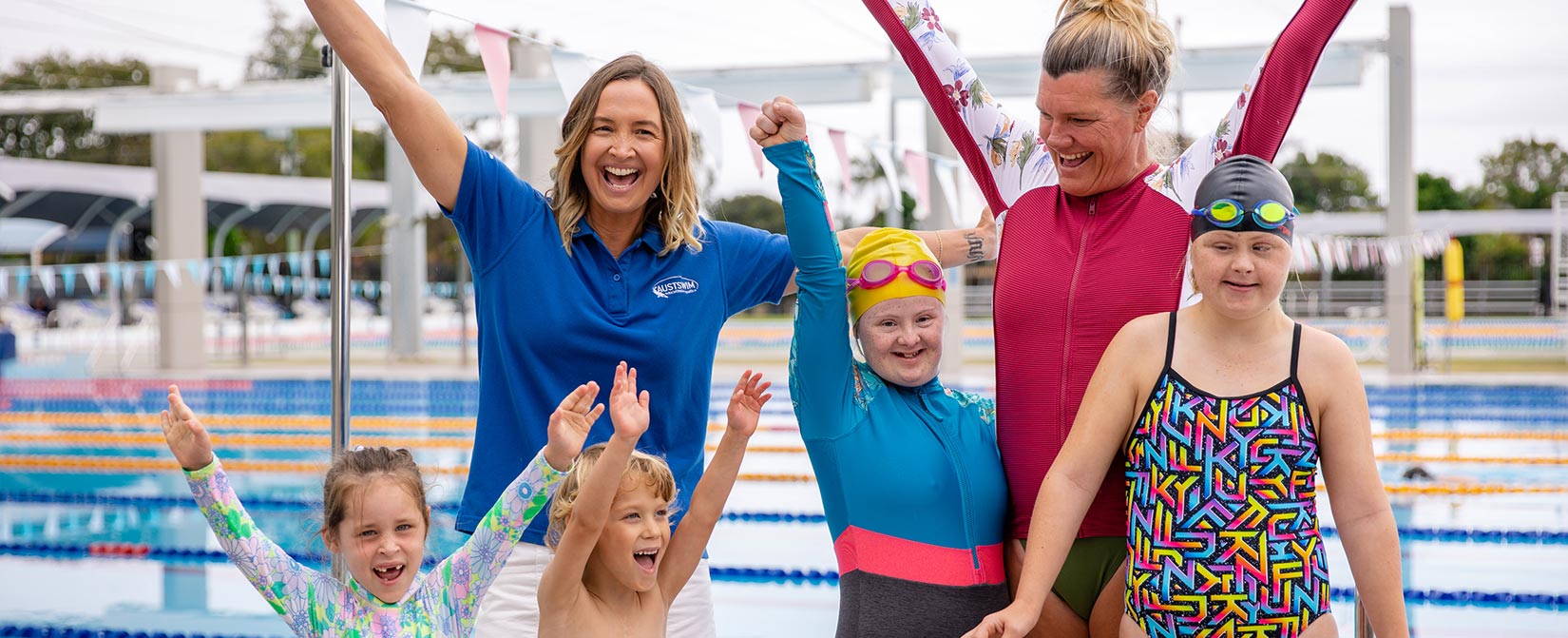 Brooke Hanson poses for photo with a group of children at a swimming pool.